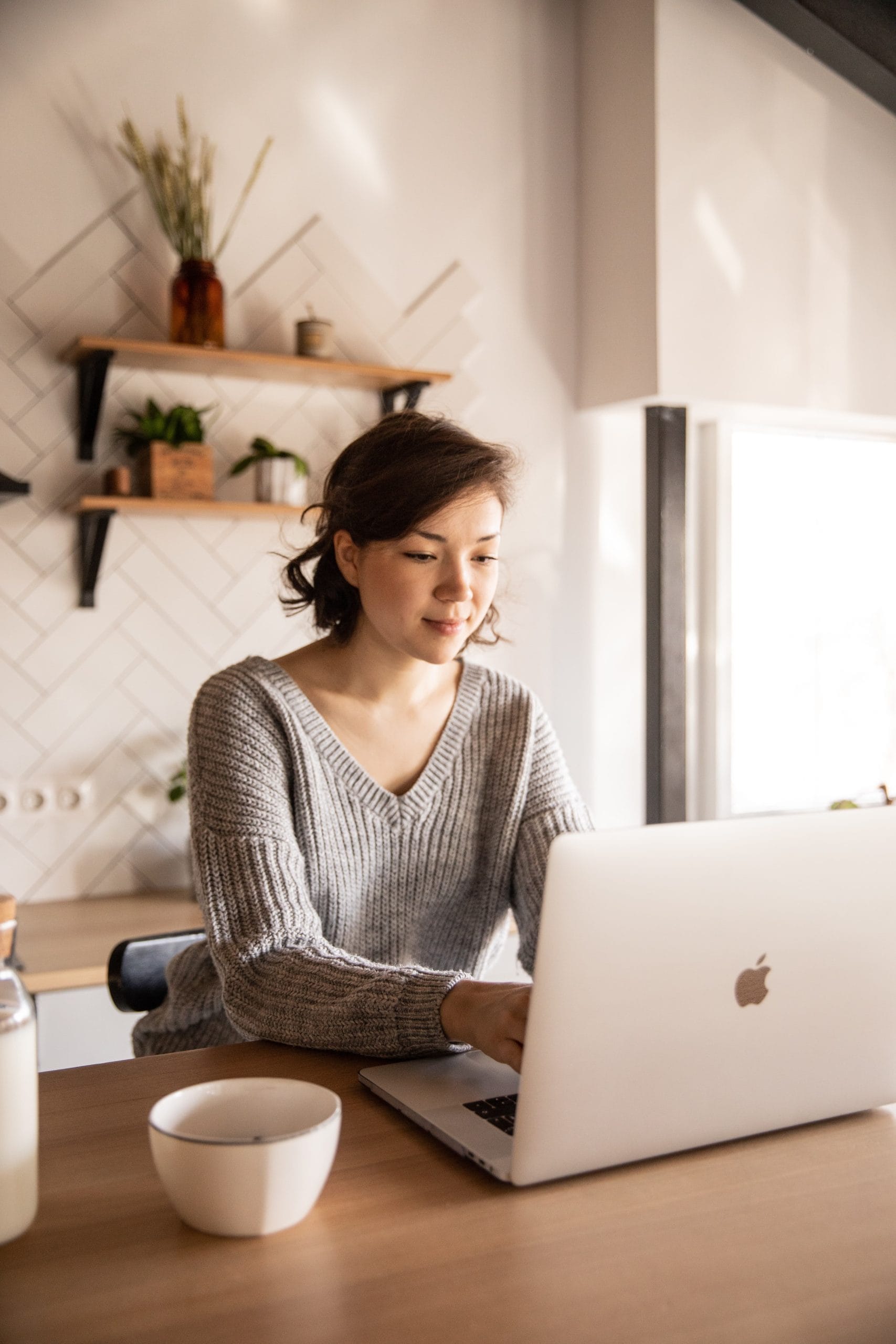 Woman in a kitchen using her computer to search for jobs online